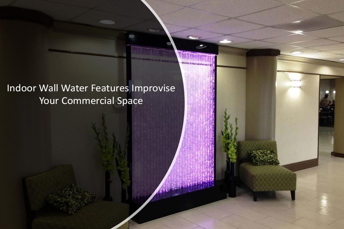 Indoor wall water feature with illuminated cascading water, enhancing commercial space aesthetics, surrounded by seating and decorative plants.