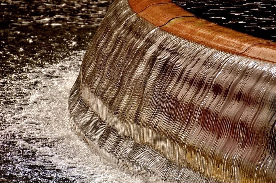 Water cascading over a curved surface of a bubble wall fountain, showcasing shimmering textures and reflections, enhancing the aesthetic appeal for corporate workspaces and home decor.