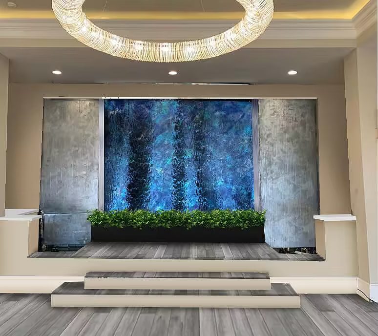 Custom indoor water wall with lush greenery, modern design, and ambient lighting, enhancing tranquil spaces in commercial and wellness environments.