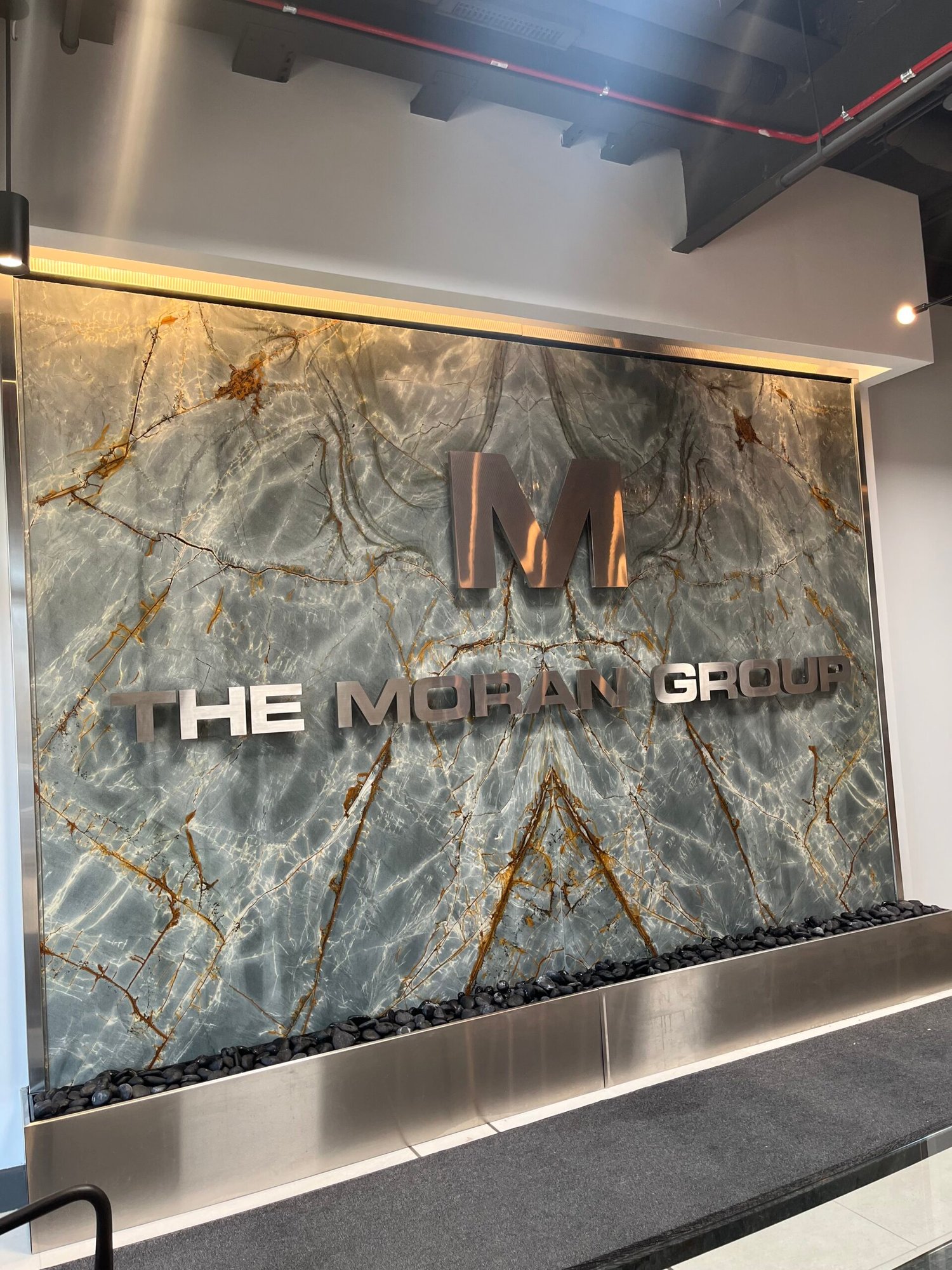 Logo Fountains 97 Granite Tile Water Wall featuring etched logo for FE Moran, enhancing the interior design of a commercial space in Northbrook, Illinois.