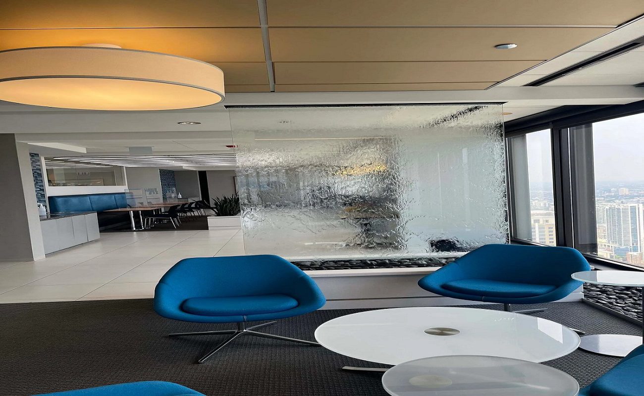 Indoor setting featuring a modern bubble wall water feature, blue chairs, and a round table, enhancing the aesthetic appeal of an office space.