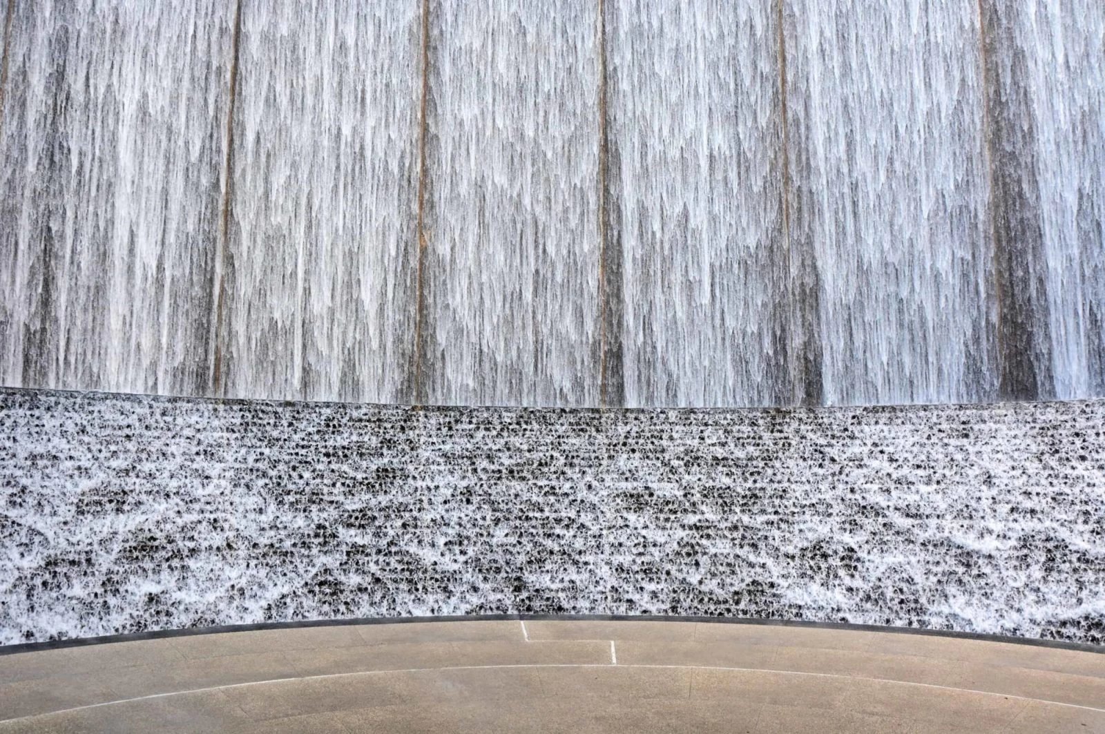 Indoor water wall feature with cascading water over a textured surface, enhancing ambiance in modern spaces.
