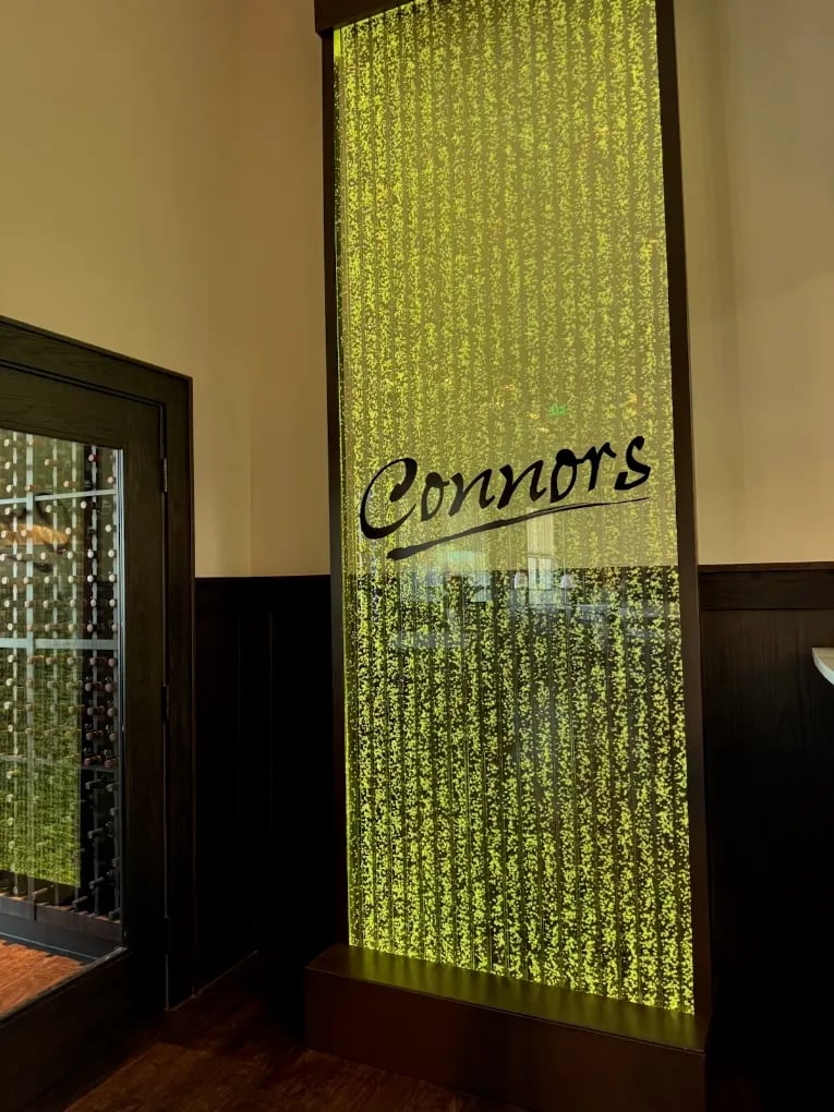 Logo Fountains 78 Vertical chamber bubble wall with custom logo "Connors" for Connors Steak & Seafood restaurant in Tallahassee, Florida, featuring illuminated water effect and modern design.