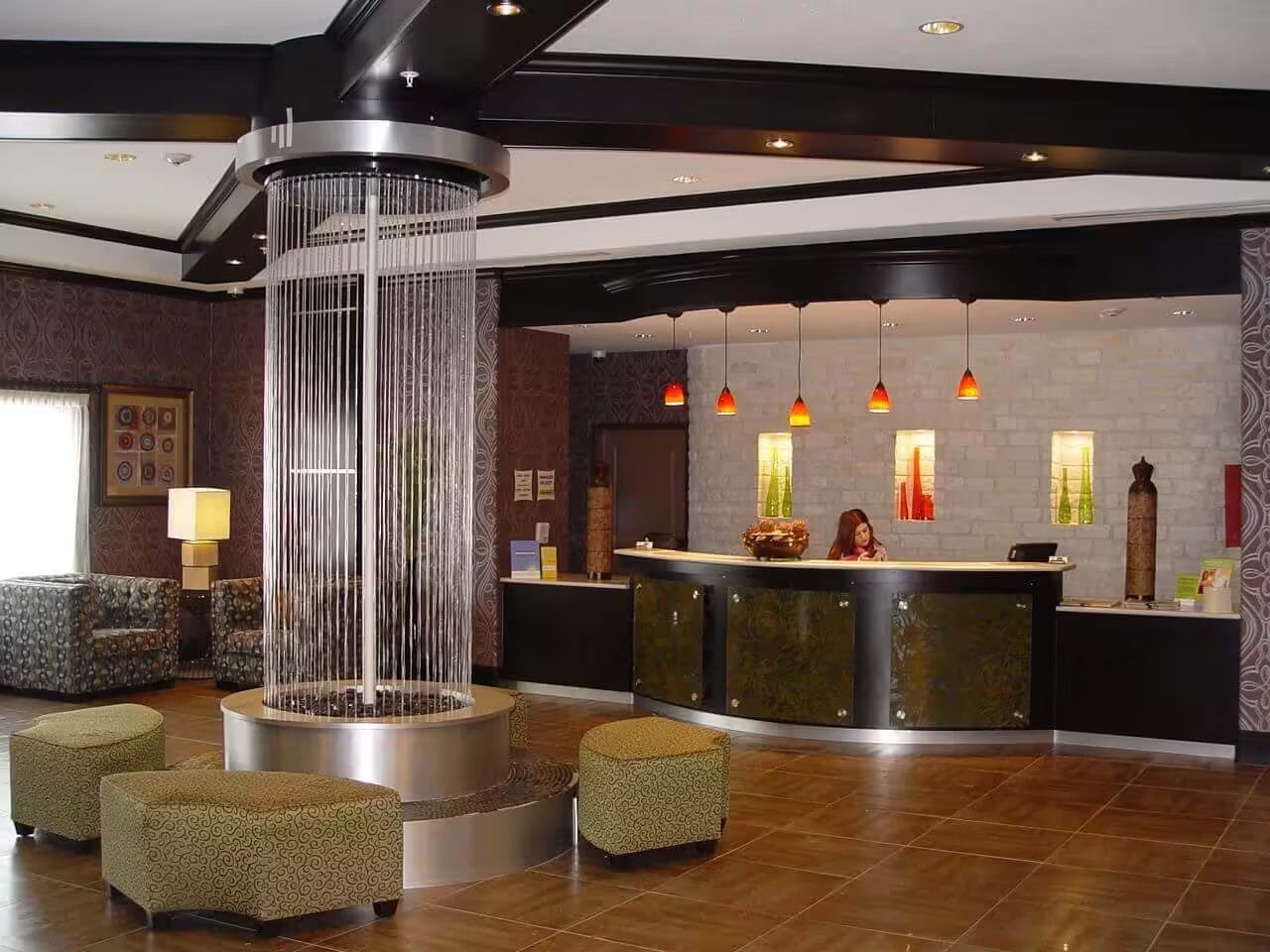 Indoor water feature with cascading water strands, modern reception area, stylish seating, and decorative lighting elements.