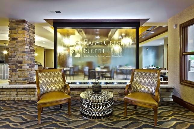 Logo Fountains 81 Glass water wall featuring the logo for Eagle Crest South, surrounded by stylish seating in a modern interior setting.