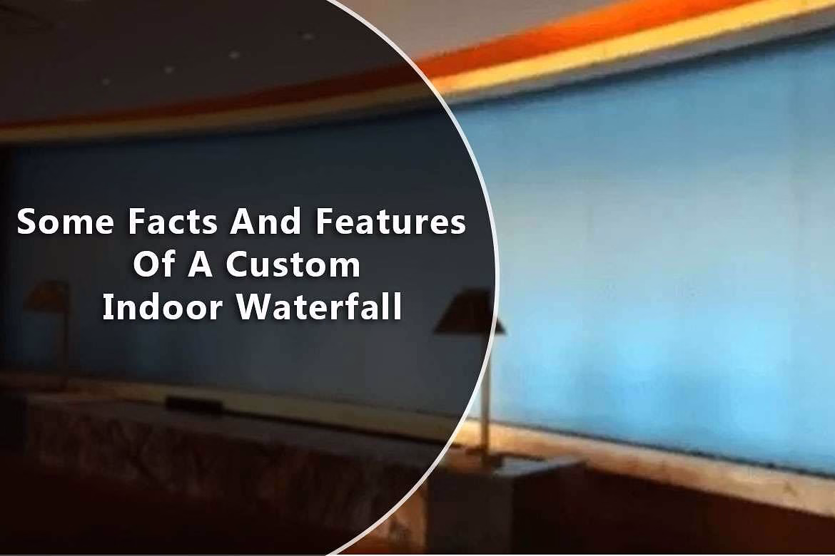 Custom indoor waterfall design featuring a glass water wall, illuminated by ambient lighting, enhancing modern interior spaces.