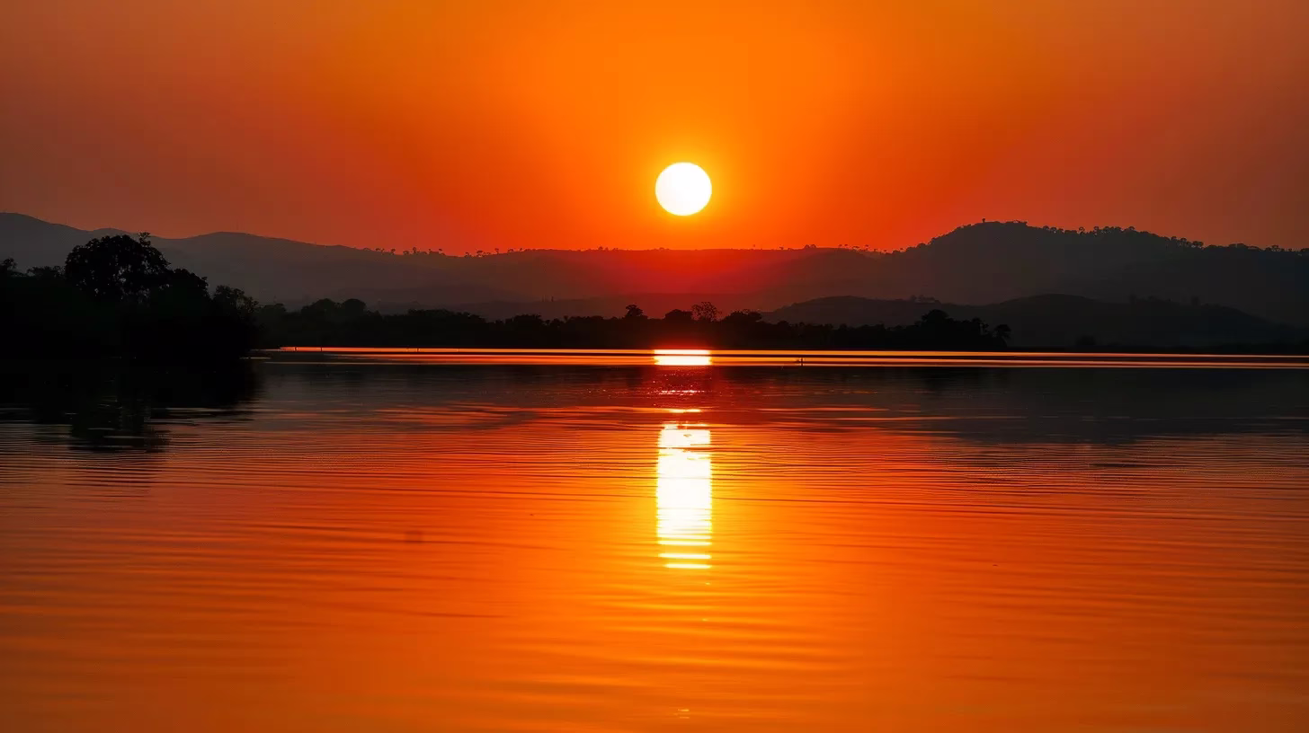 Benefits of Rain Water Harvesting for Sustainable Living 3 a vivid sunset casts a warm golden glow over a tranquil lake, with silhouettes of majestic mountains reflecting perfectly on the water's surface.