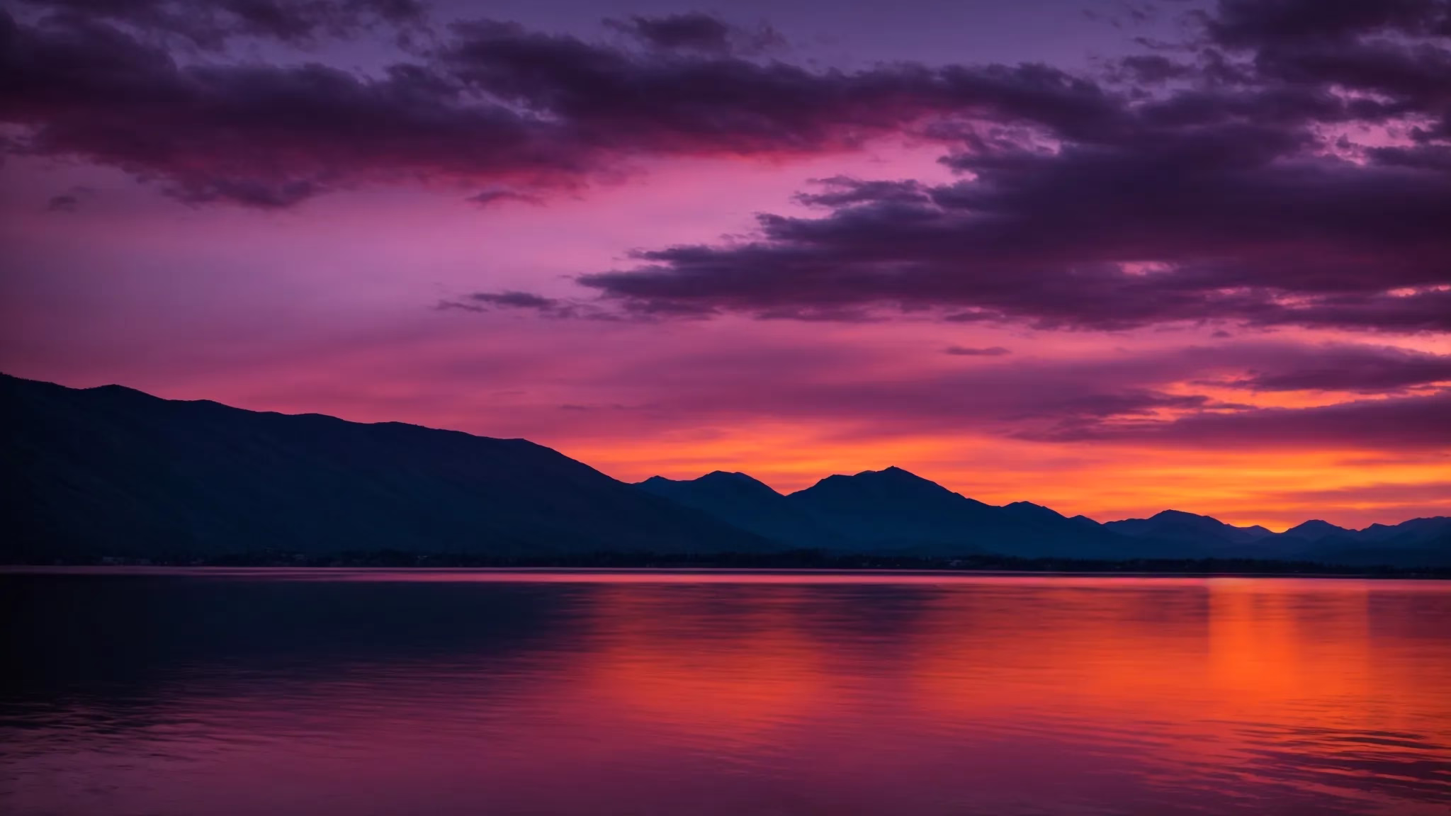 Fountain Large Options to Transform Your Landscape 2 a breathtaking sunset illuminates a tranquil lake, casting vibrant reflections of fiery oranges and purples on the water’s surface, framed by silhouetted mountains in the background.