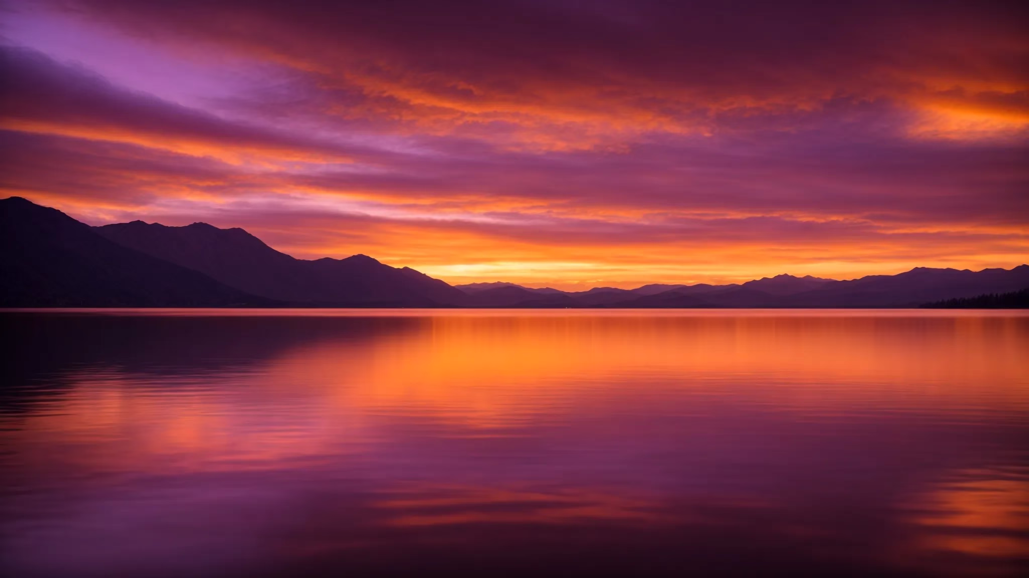 Interior Water Feature Ideas for Serene Living Spaces 3 a vibrant sunset casts a golden glow over a serene lake, with silhouetted mountains reflected in the water and wisps of clouds painted in hues of orange and purple.