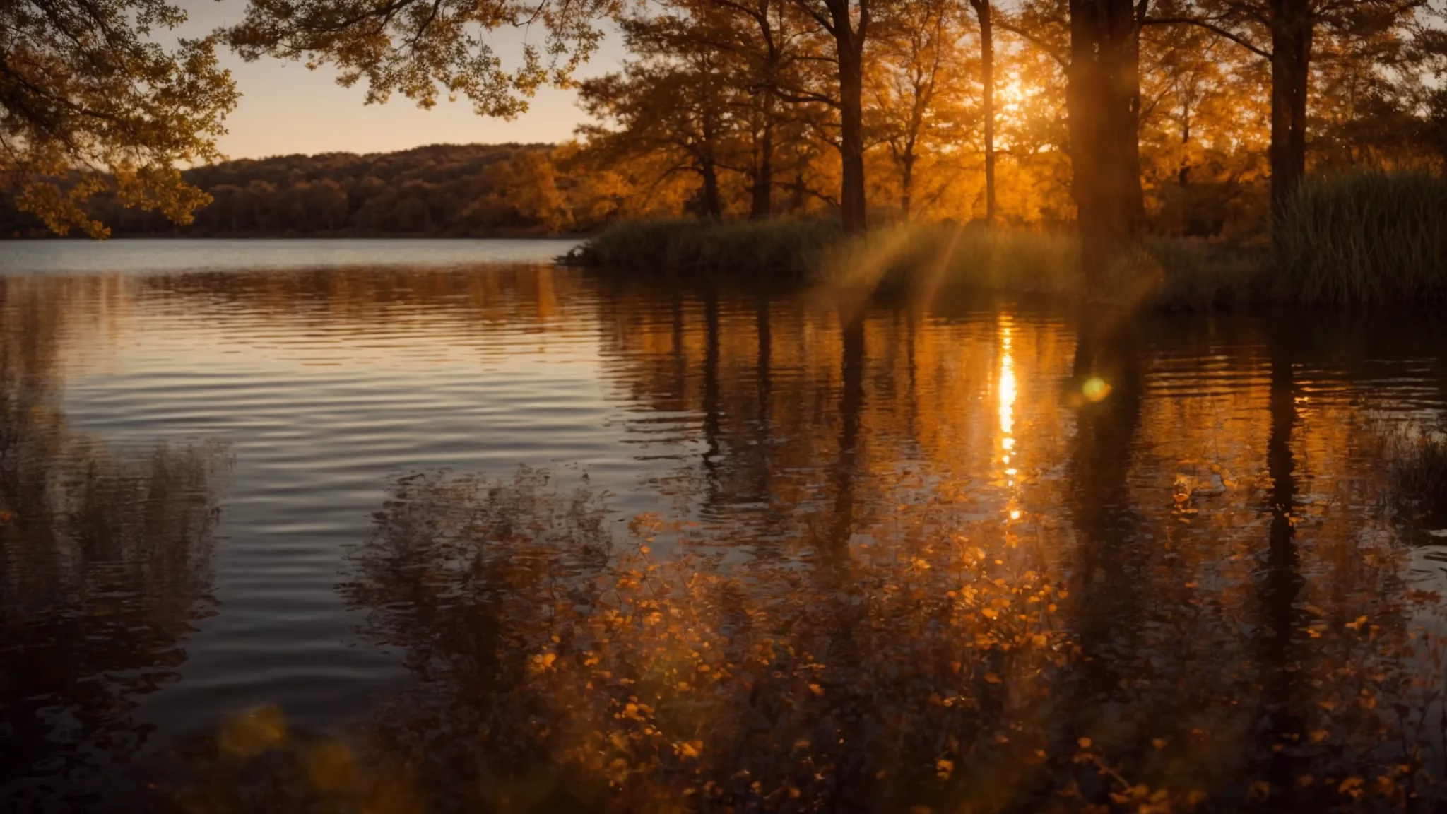 Enhance Your Yard With Beautiful Outdoor Waterfalls for Sale 1 a vibrant sunset casts a warm, golden glow over a tranquil lake, with silhouette trees framing the scene and reflecting softly on the water's surface.