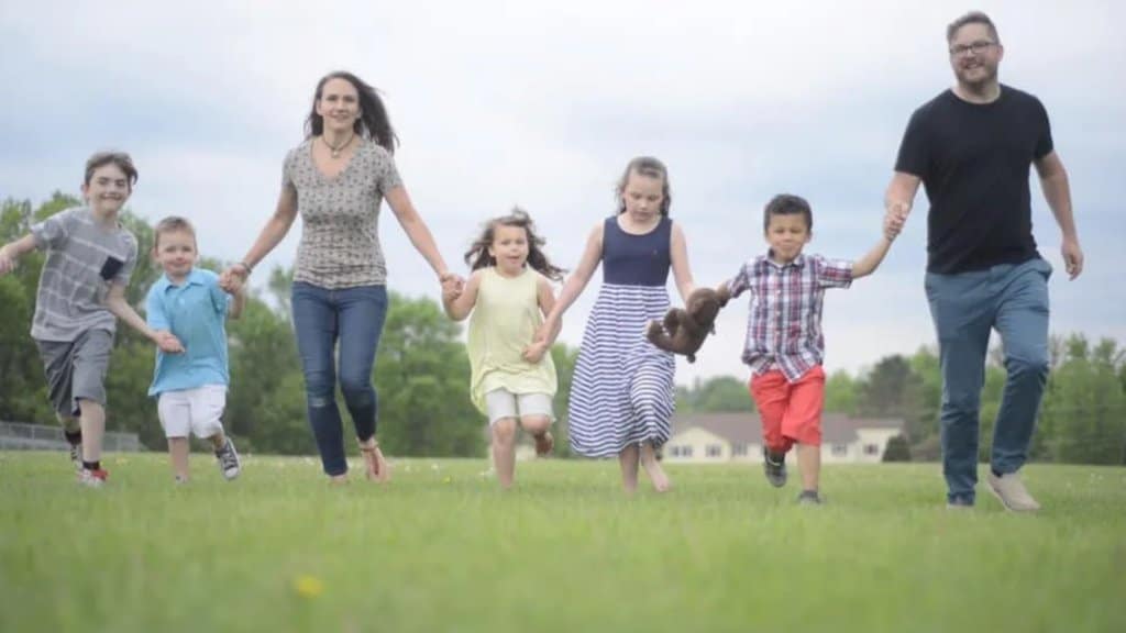 Jessica Hurlbut and family running through a grass field