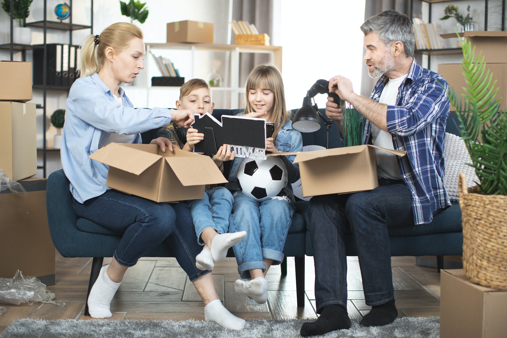 Young parents with kids unpacking boxes during relocation to new appartment
