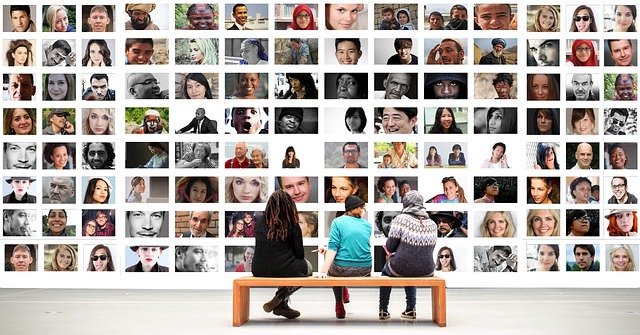 3 personnes qui regardent un mur de photos avec plein de portraits, équipe en construction