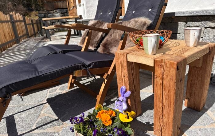 Liegestühle auf der Terrasse Chalets Eggerfeld mit osternest und Frühlingsblumen