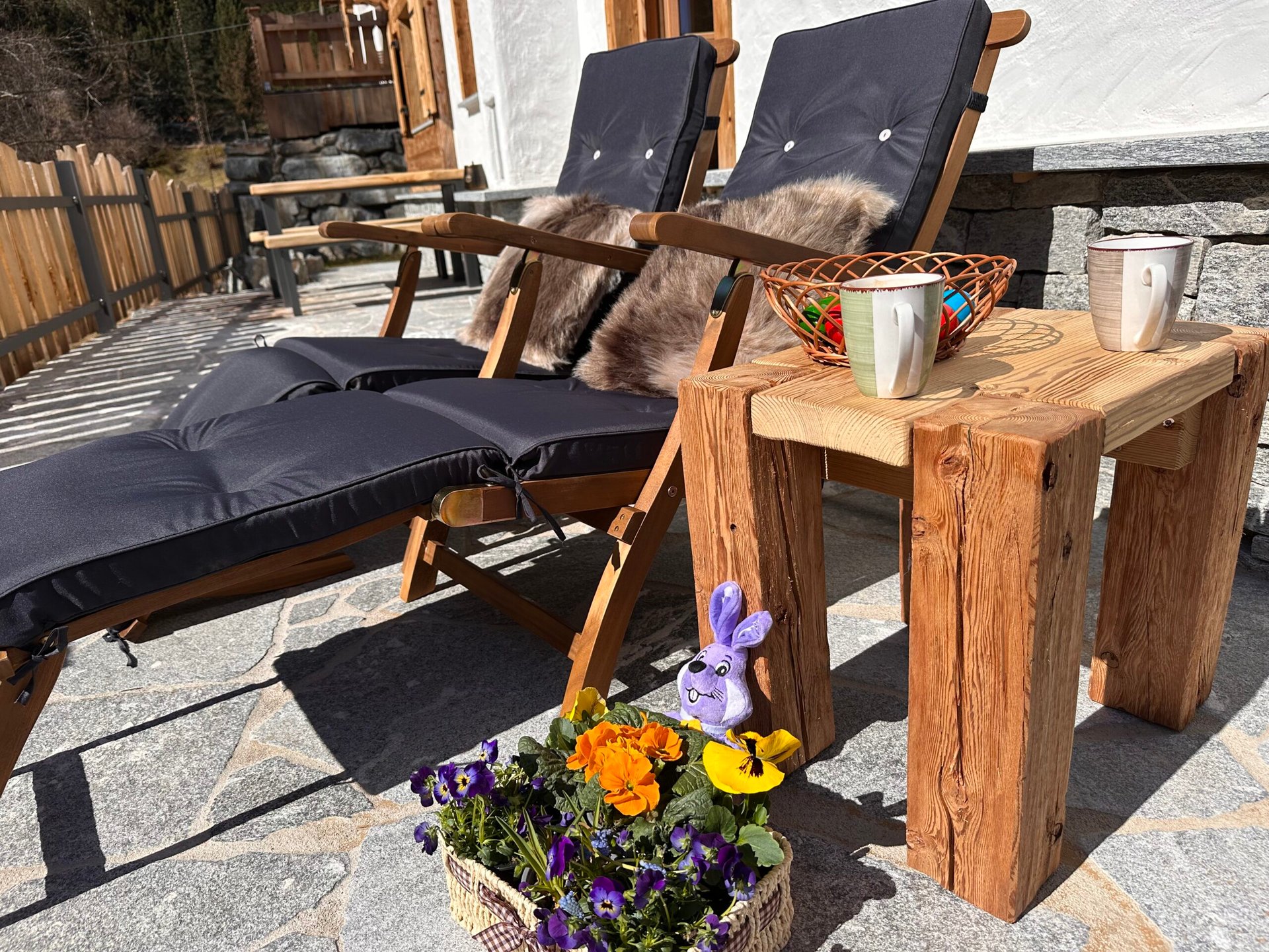 Liegestühle auf der Terrasse Chalets Eggerfeld mit osternest und Frühlingsblumen