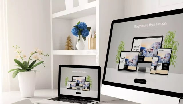 Ein Laptop und ein Desktop-Monitor zeigen ein Webdesign-Konzept in einem hellen, modernen Arbeitsbereich.