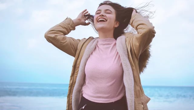 Eine Influencerin posiert am Strand, während ihr Haar anmutig im Wind weht.