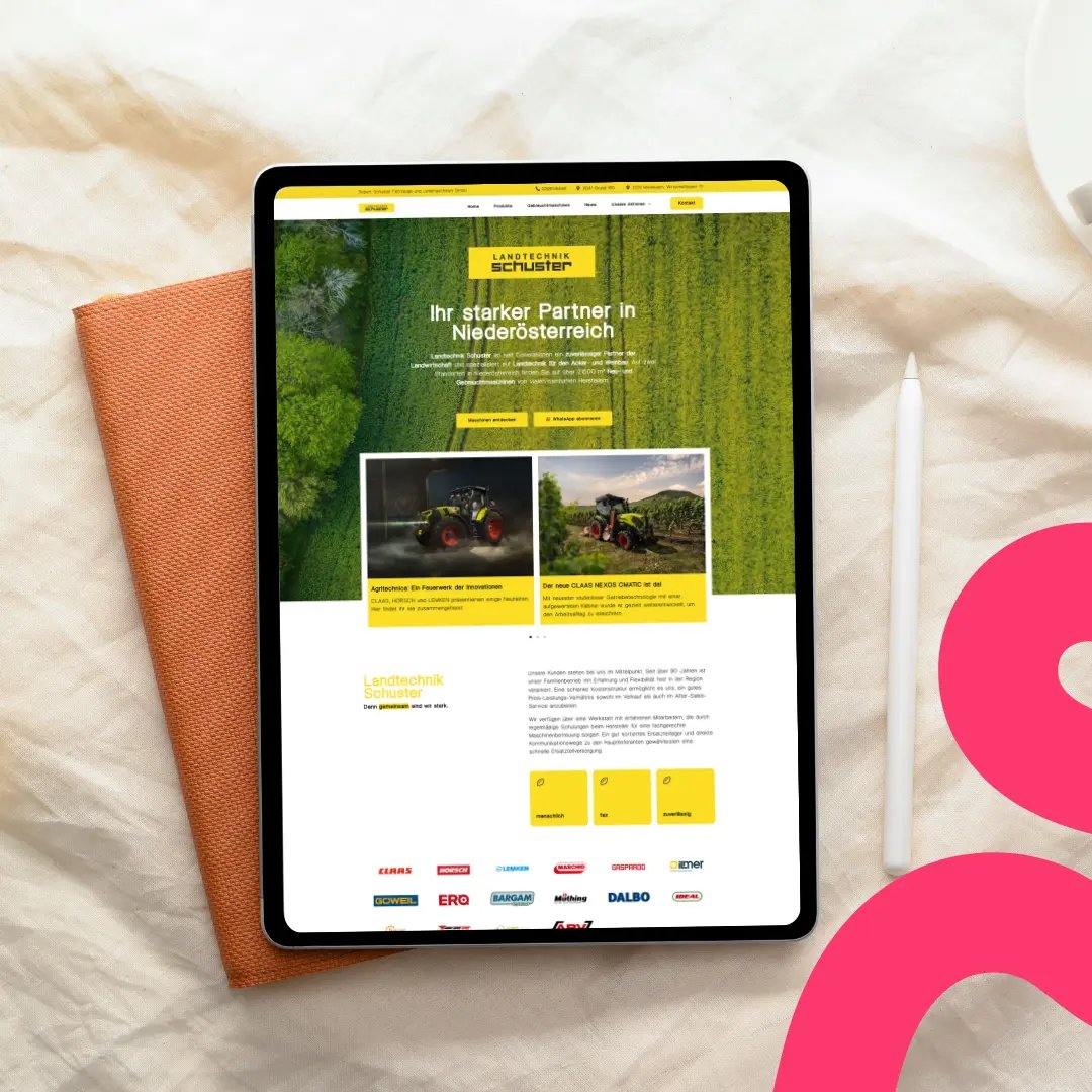Ein Tablet, auf dem die deutschsprachige Landtechnik Schuster-Website mit Bildern von Traktoren auf einem orangefarbenen Stoff neben einem weißen Stift und einem rosa Grafikelement abgebildet ist.