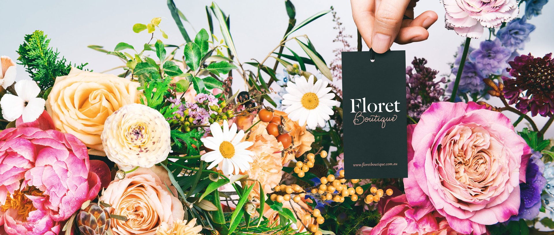 A person holding a flower tag in front of a bunch of flowers.