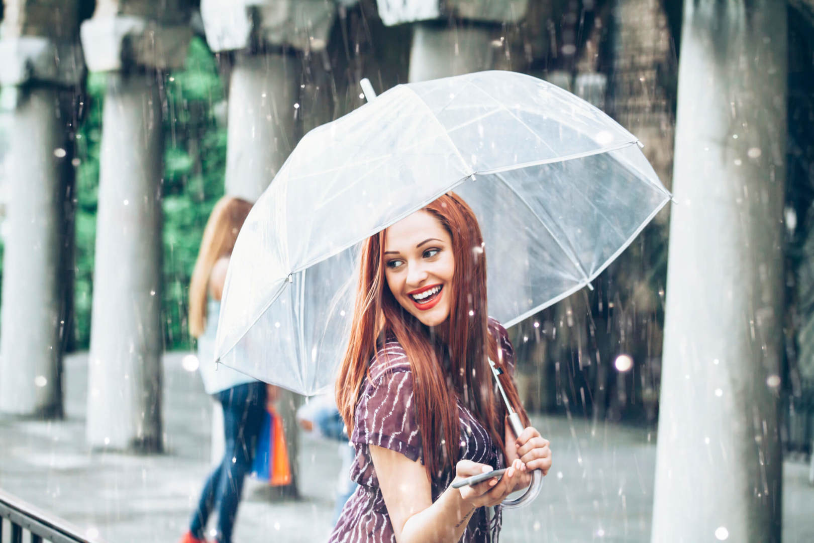 Happy young woman walking with umbrella under the rain my insurance covers it