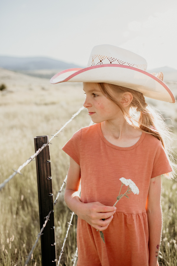6G4A3320 Little cowgirl with flowers in field portrait
