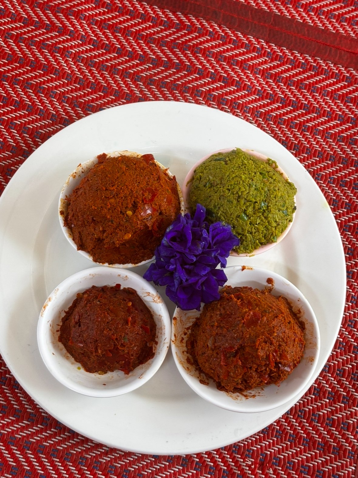Four curry pastes in vibrant colours, with a purple edible flower. Part of a Thai cooking class