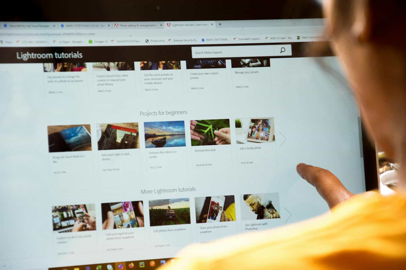 Interactive Learning Platforms, Woman exploring Lightroom tutorials on computer screen, perfect for online education themes.