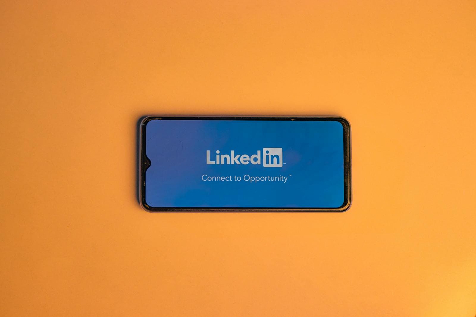 Linkedin, Group, Networking, Lead Generation, Networking, Smartphone showing LinkedIn login on vibrant orange background, symbolizing connectivity.