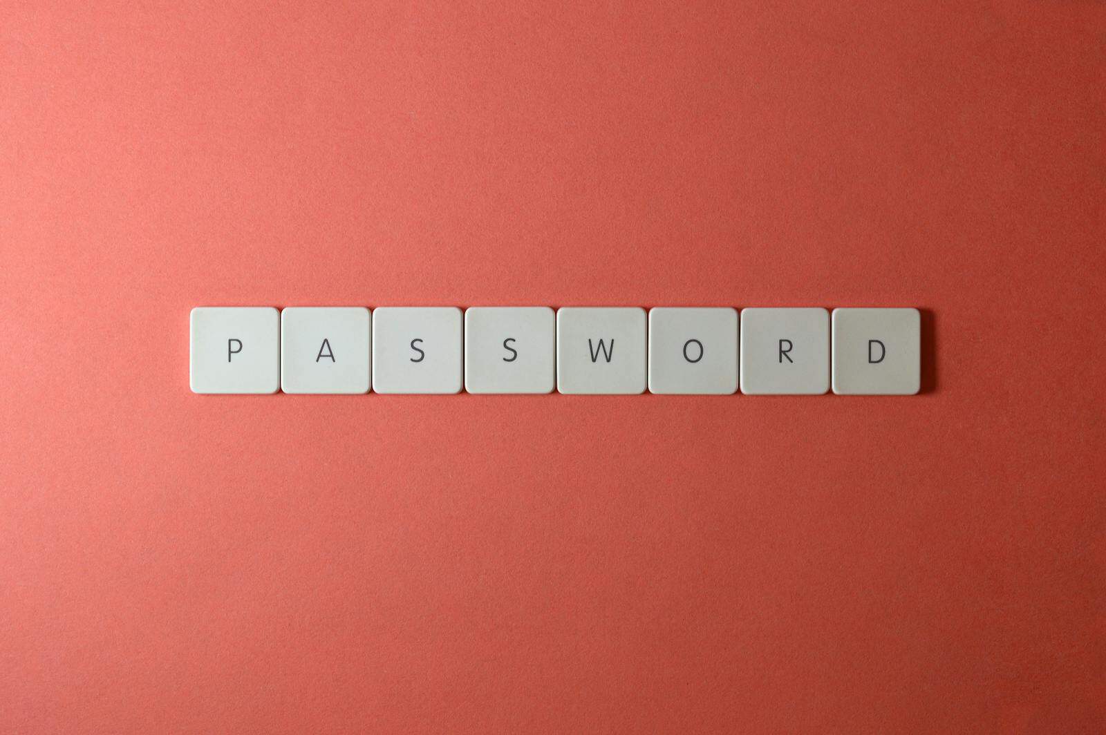 data breach, Focus on password security with white keyboard tiles spelling 'PASSWORD' on a coral background.