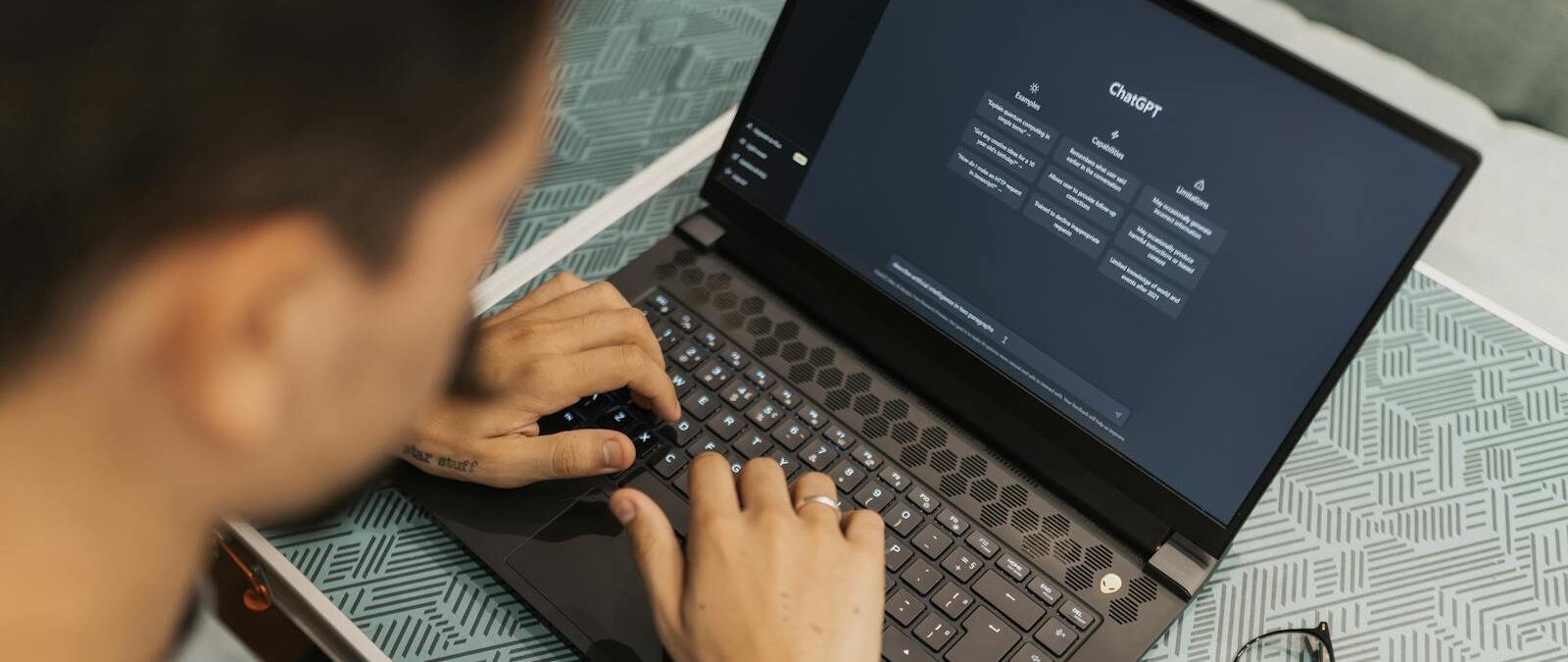 A man working on a laptop with AI software open on the screen, wearing eyeglasses. Business, ai