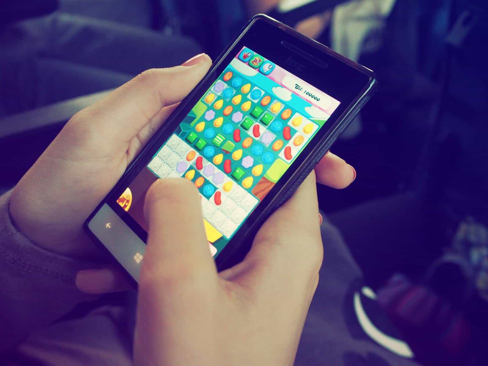 User Engagement, Hands holding a smartphone with a colorful puzzle game on the screen, displaying modern technology.