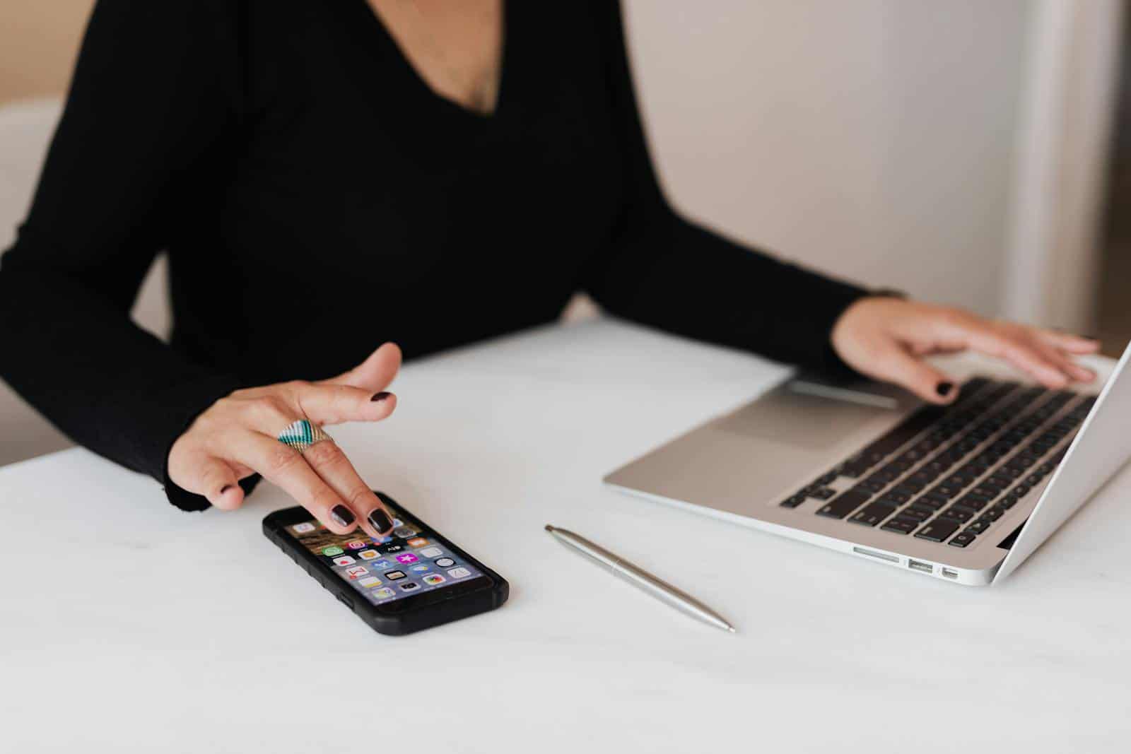 Marketing, quiz, quizzes, A professional woman multitasking with a smartphone and laptop at an office desk.