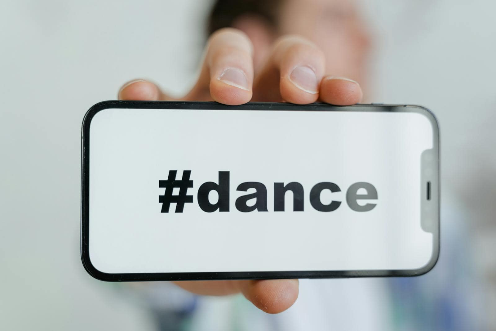 Instagram, Marketing, Algorithm, Close-up of a phone screen displaying the #dance hashtag, held by an adult.