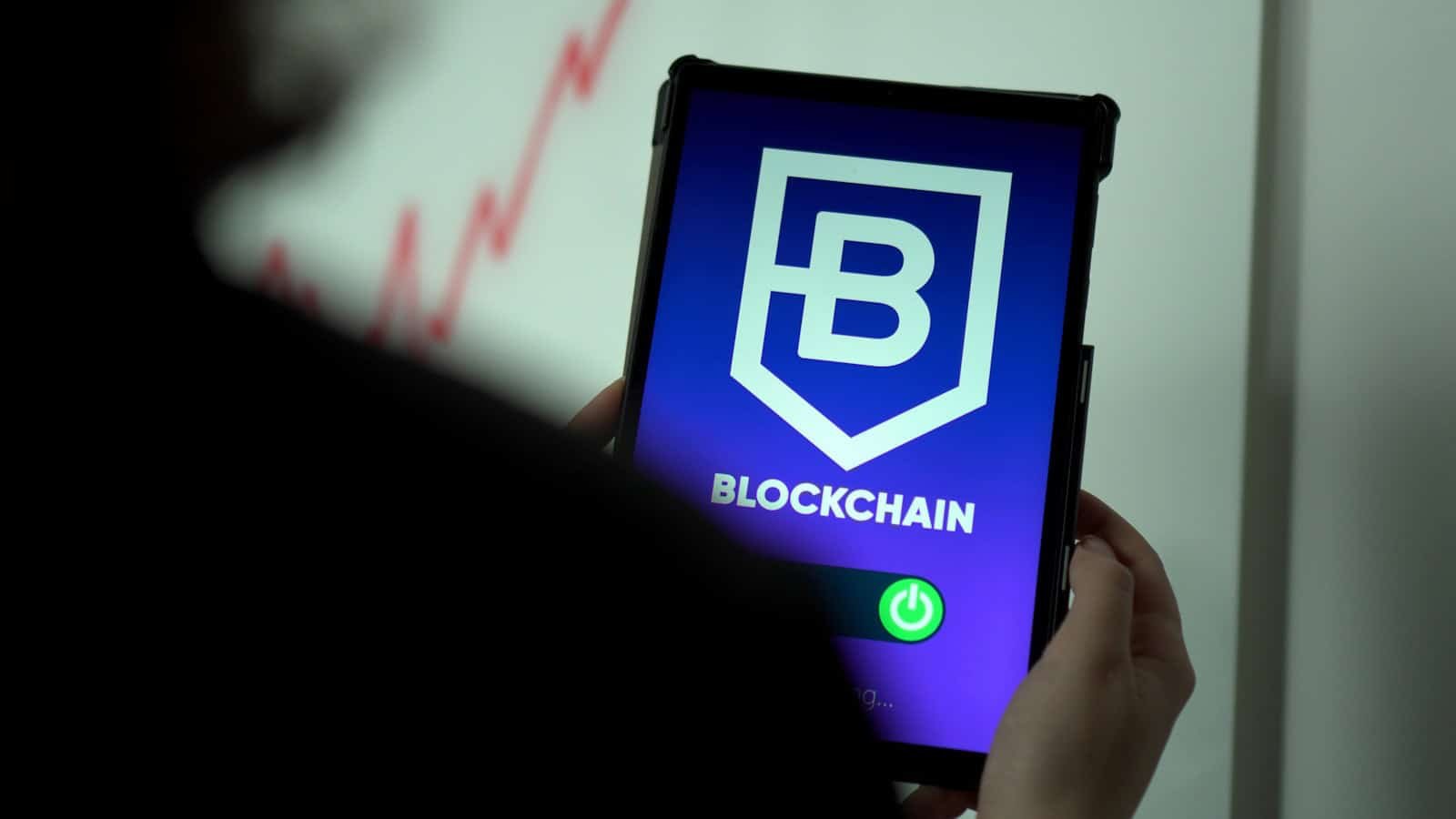 Blockchain Technology, a person holding a cell phone with a blockchain logo on it