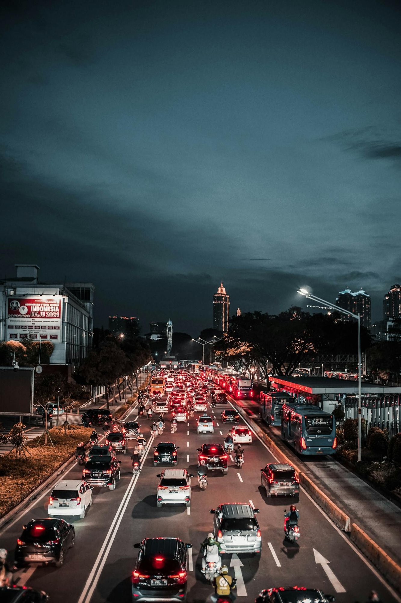 Various vehicles driving on asphalt street during traffic jam in modern city district in evening