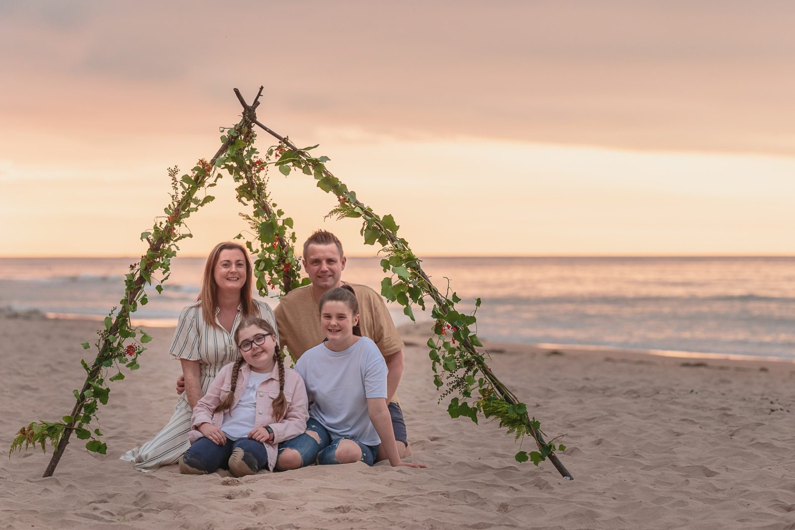 What is family photography - 5 Tips 1 A Northern Ireland family poses on the beach with a teepee captured by NI photographers.