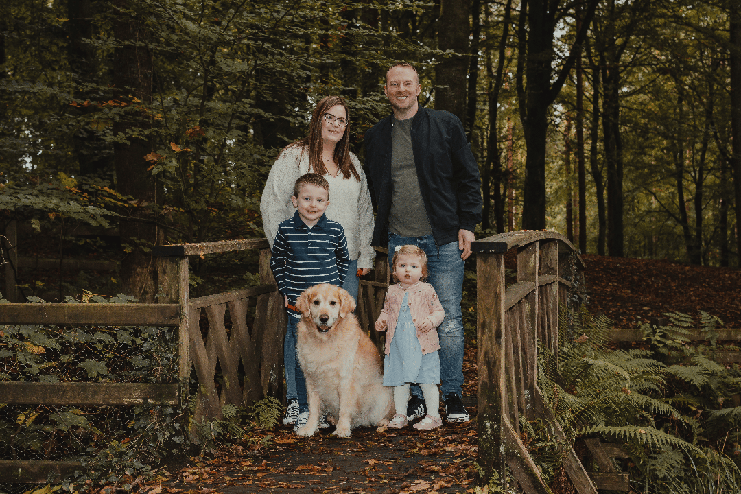 F.A.Q. 1 Family Photographer A family posing on a bridge in the woods with their dog.