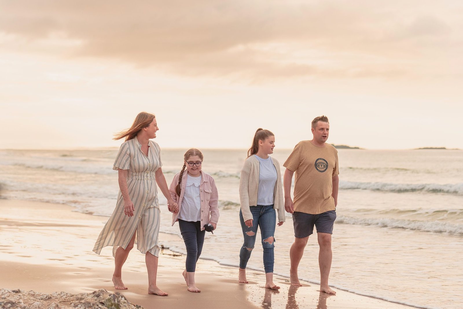 The Art of Beach Portrait Photography: Essential Tips for Stunning Beach Portraits 3 A Northern Ireland family photographer captures a family walking on the beach at sunset.