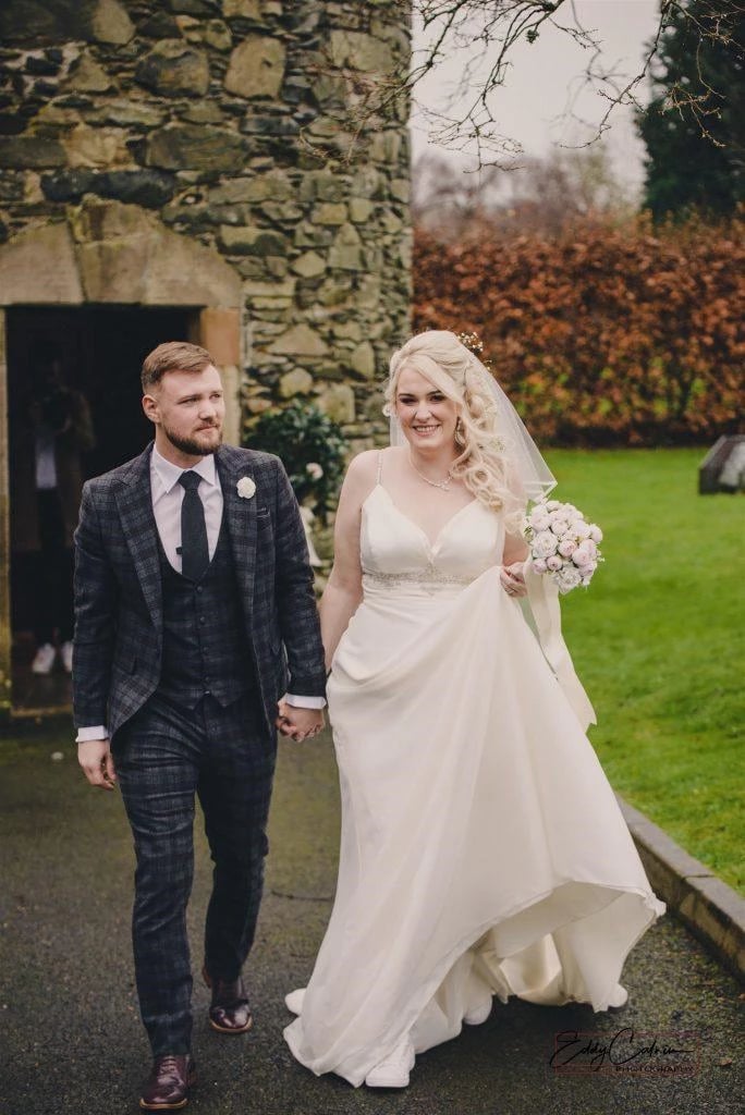 Kiltonga Hall Weddings 1 Family Photographer A bride and groom walking in front of a stone building.