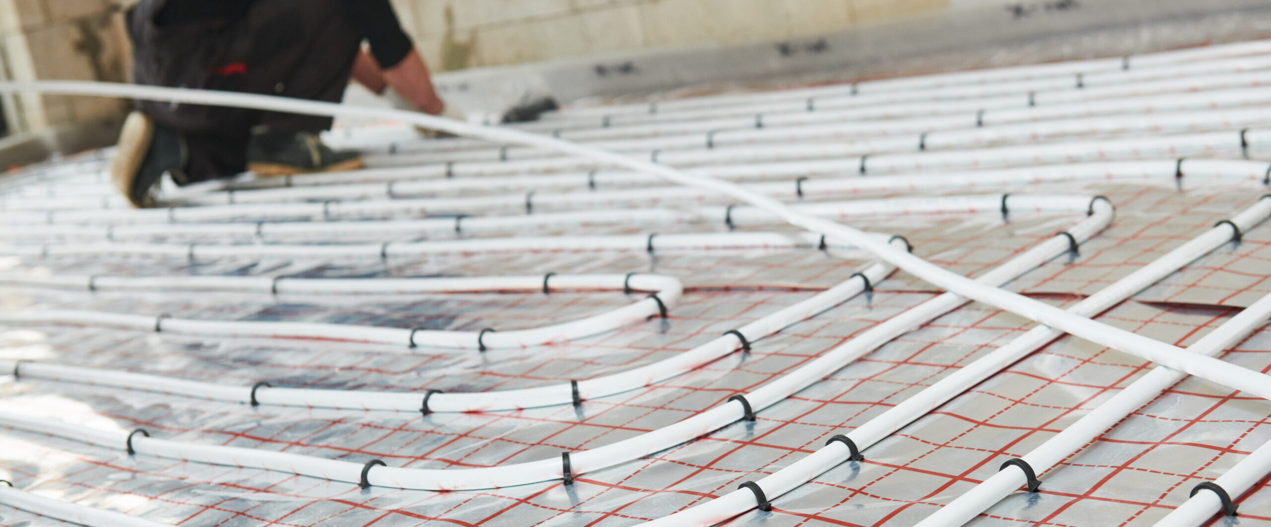 Floor heating system. Pipe fitter mounting underfloor heating. warm floor system with hot water circulation in pipes