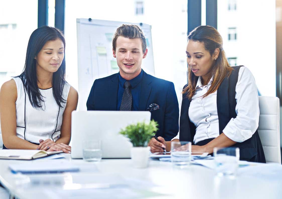 a men and 2 women reviewing reports in a laptop