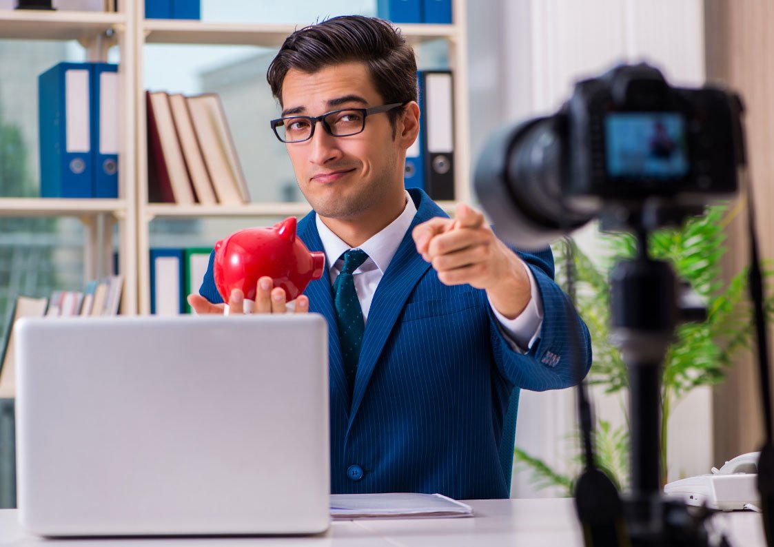 man holding a piggy bank while pointing at the camera