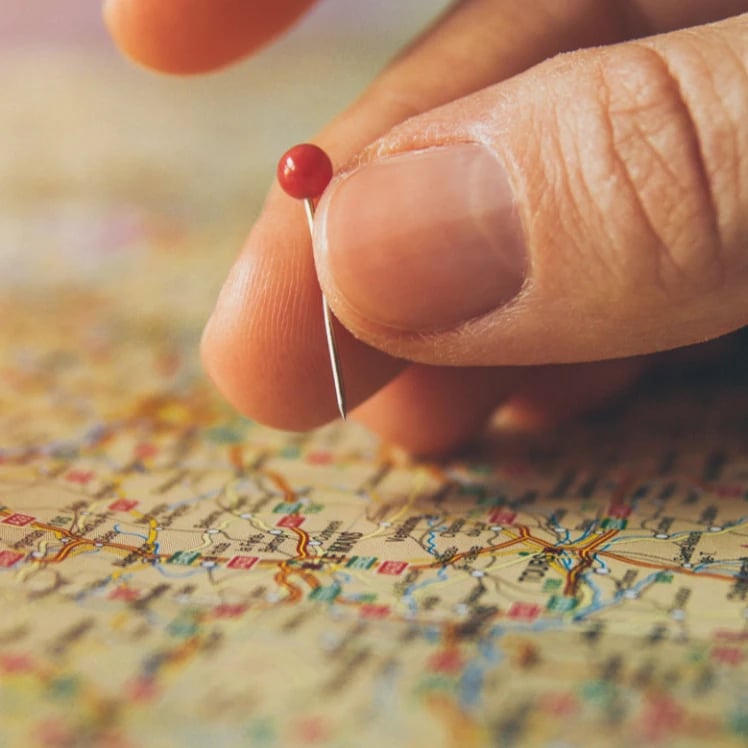 A pushpin going into a map