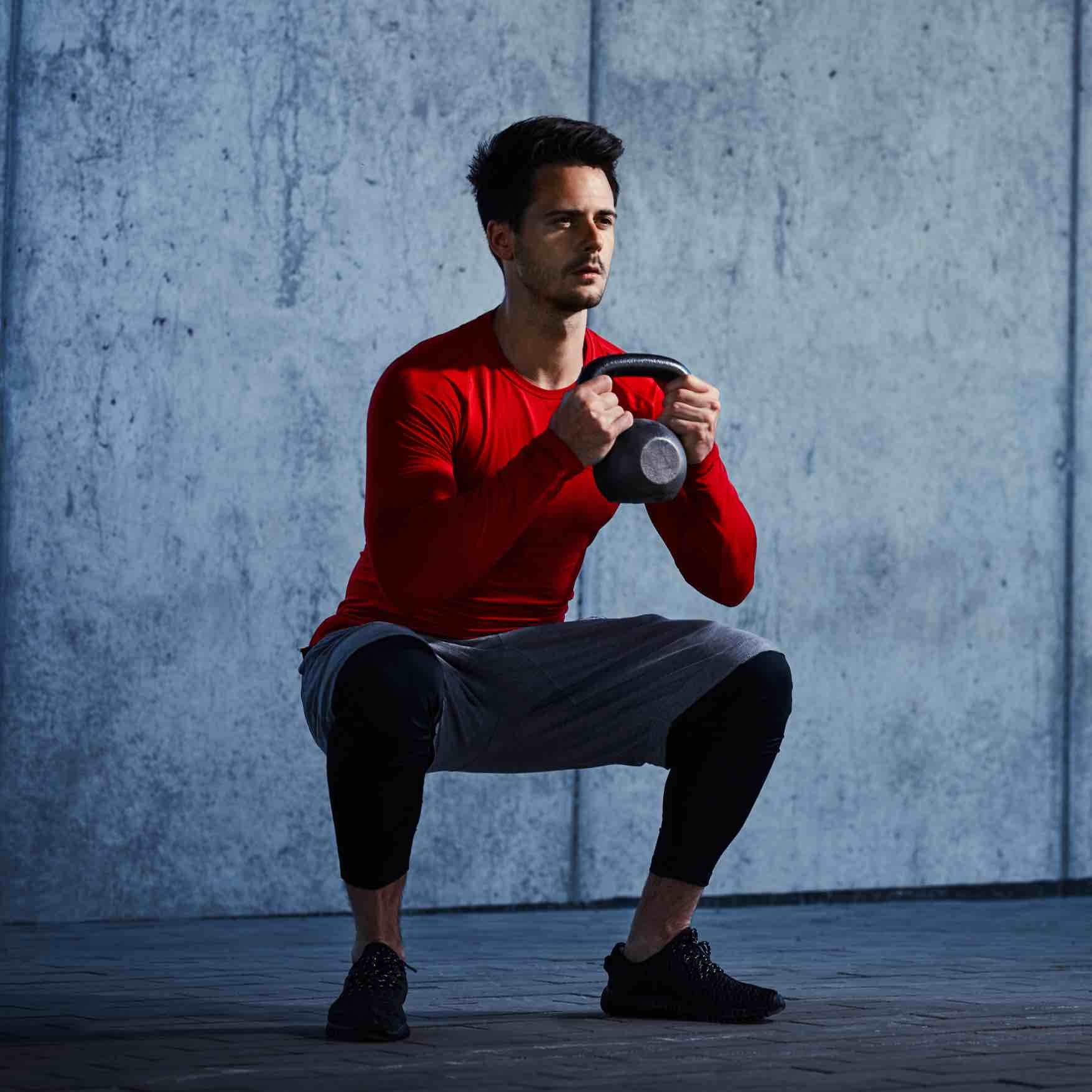 Man Squatting With Kettlebell Man Squatting With Kettlebell