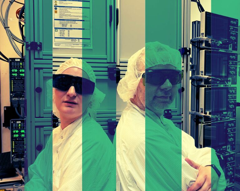 Two individuals in lab coats and protective eyewear stand in a state-of-the-art laboratory, specializing in Mikrosystemtechnik, with technical equipment in the background, overlaid with green stripes.